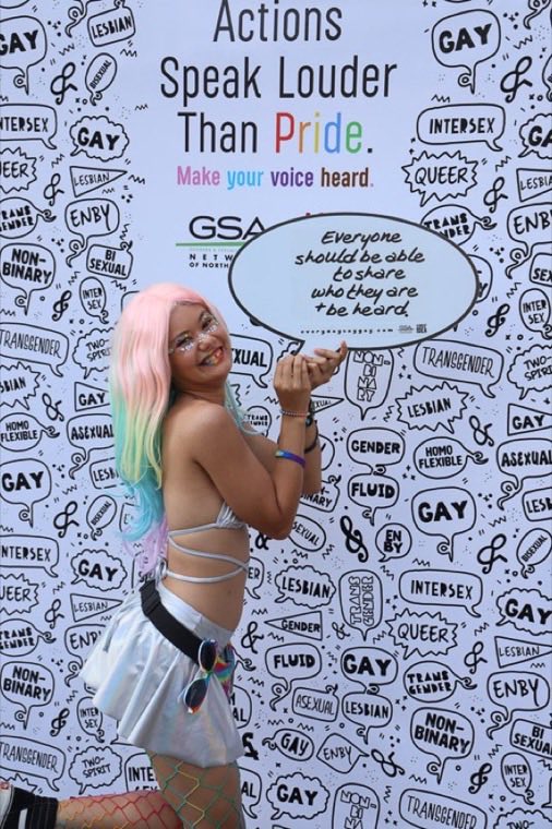 Community member at a Pride event with a speech-bubble backdrop
